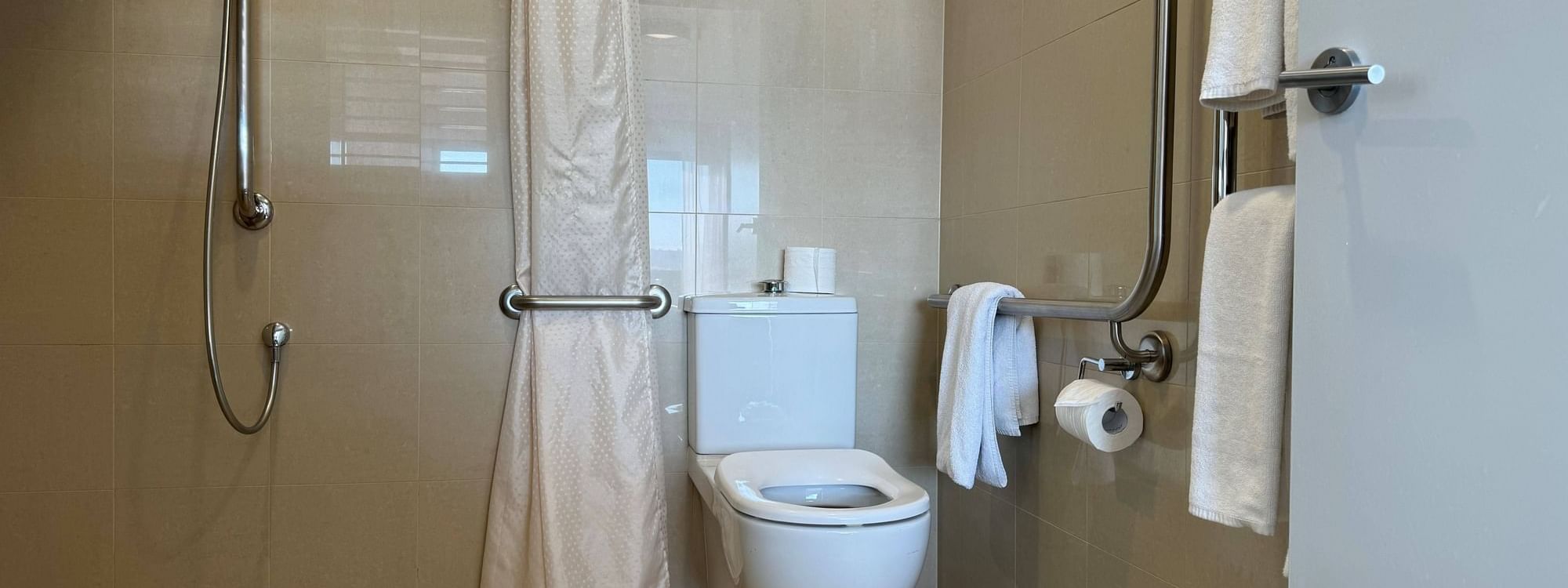 Bathroom with an accessible shower, toilet with grab bars, and towels in Accessible Room at Novotel Barossa Valley Resort