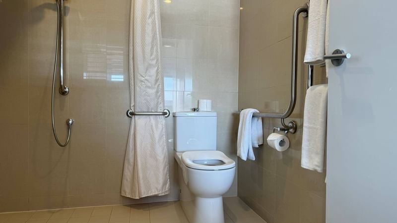 Bathroom with an accessible shower, toilet with grab bars, and towels in Accessible Room at Novotel Barossa Valley Resort