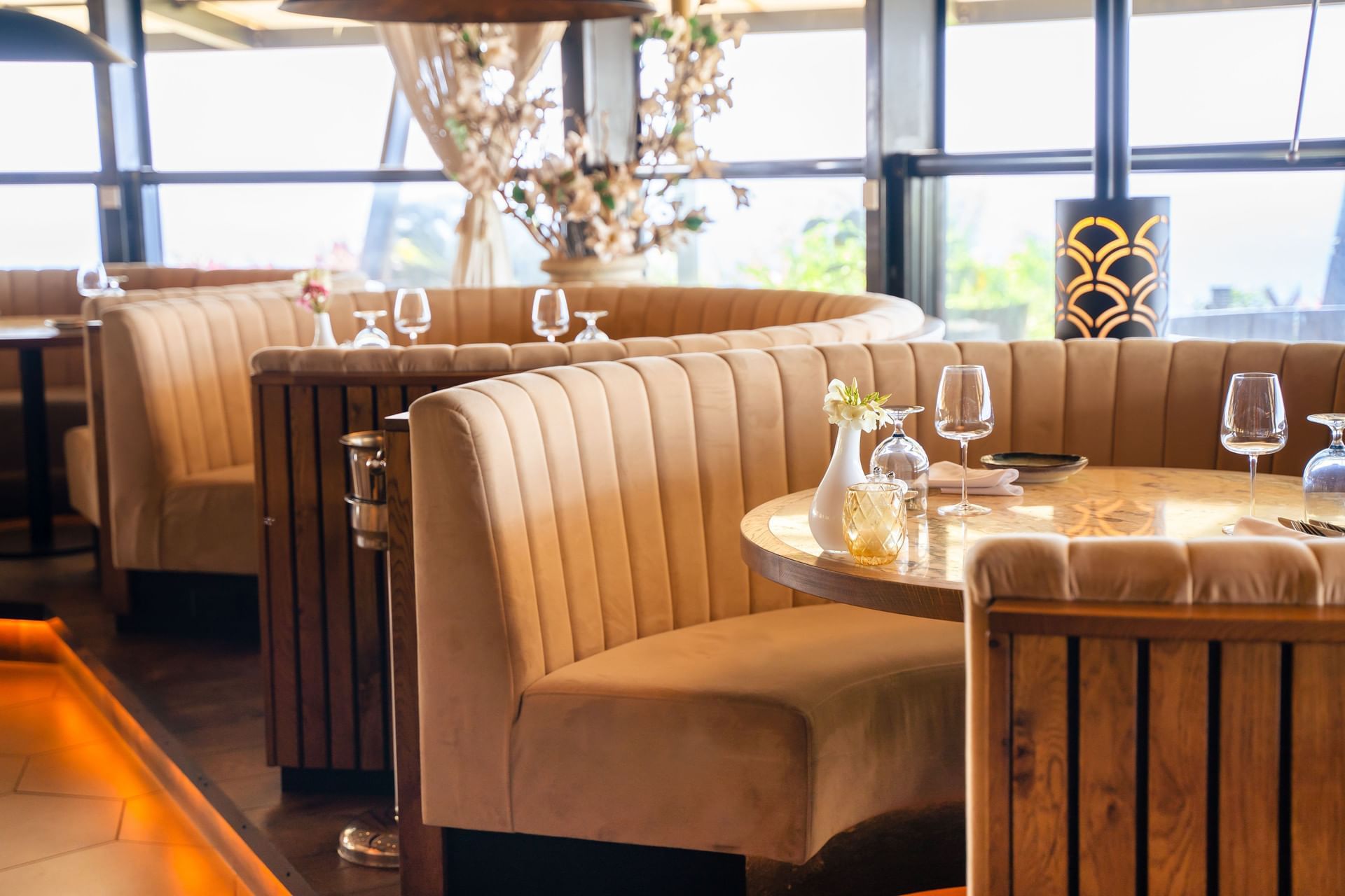 Interieur van Breeze Restaurant met beige comfortabele zitplaatsen en glaswerk bij de grote ramen in Golden Rock Resort