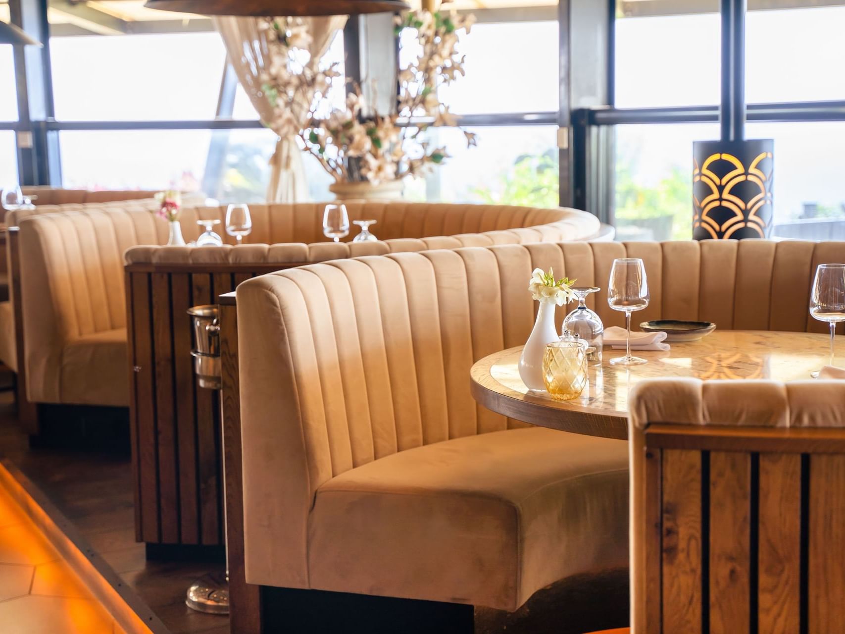 Breeze Restaurant interior featuring plush beige seating and glassware by the large windows at Golden Rock Resort