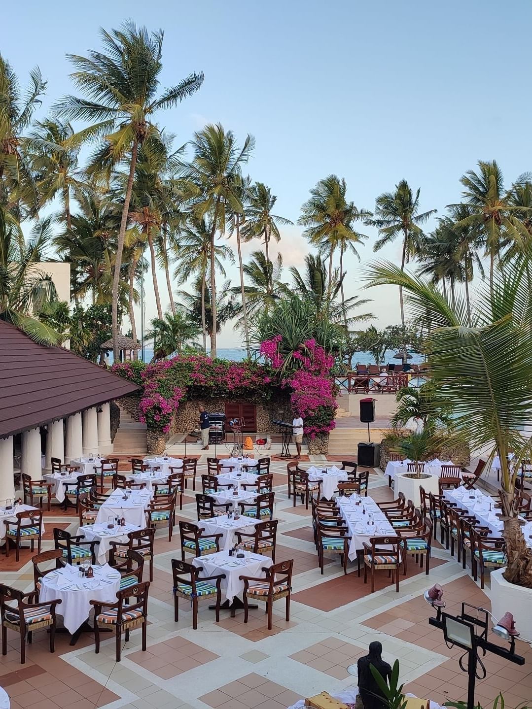 A serene outdoor dining area with palm trees and tables at Serena Beach Resort & Spa in Mombasa.