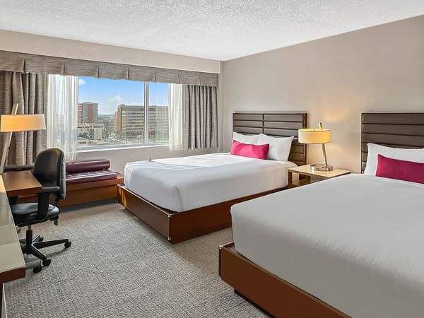 Hotel bedroom with two queen beds, work desk, and TV