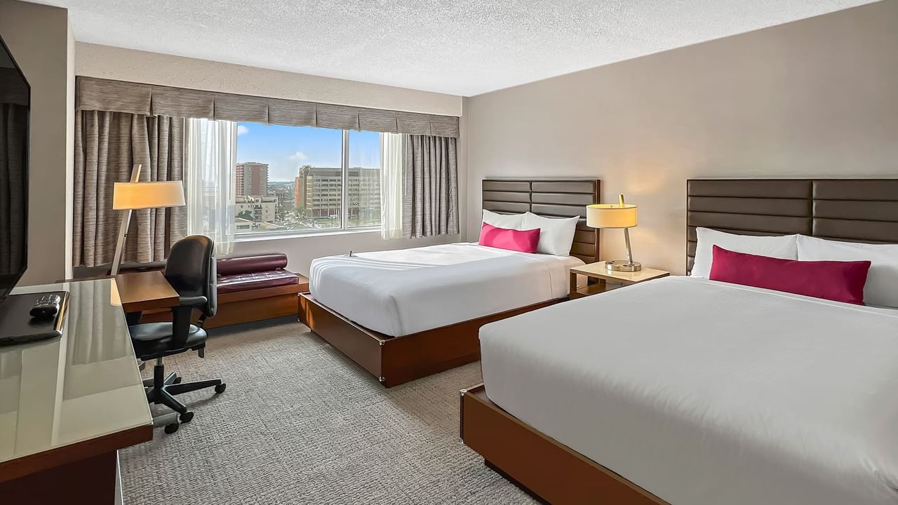 Hotel bedroom with two queen beds, work desk, and TV