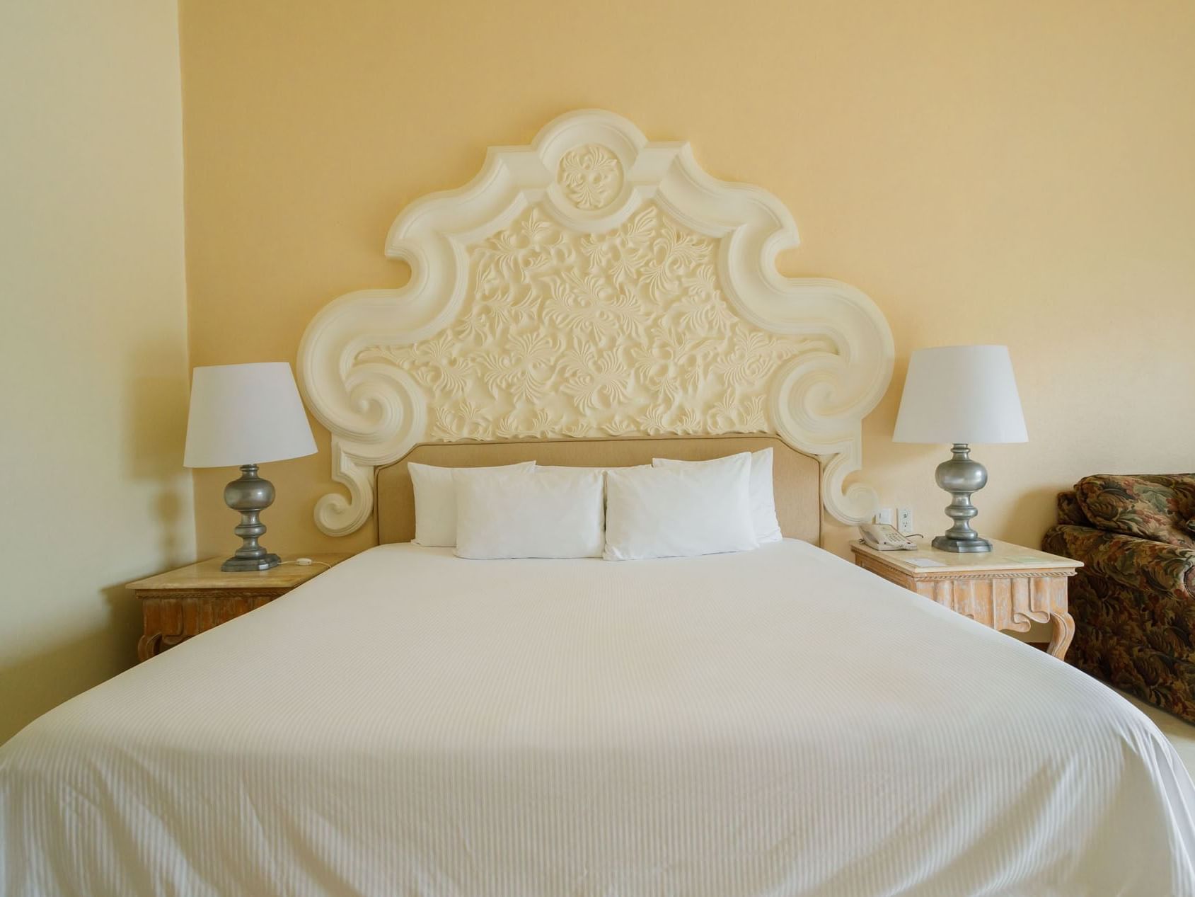 Ornate white headboard and plush king bed in King Grand Class at Quinta Real Acapulco