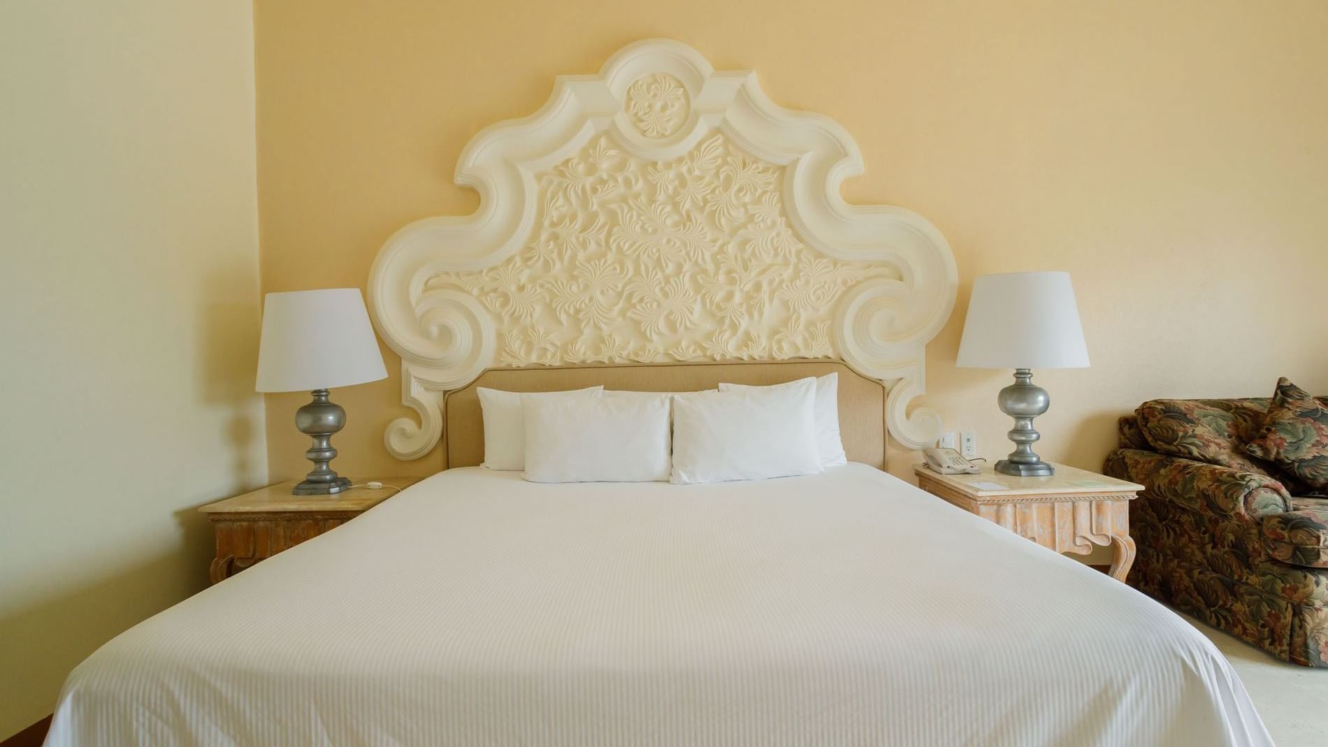 Ornate white headboard and plush king bed in King Grand Class at Quinta Real Acapulco