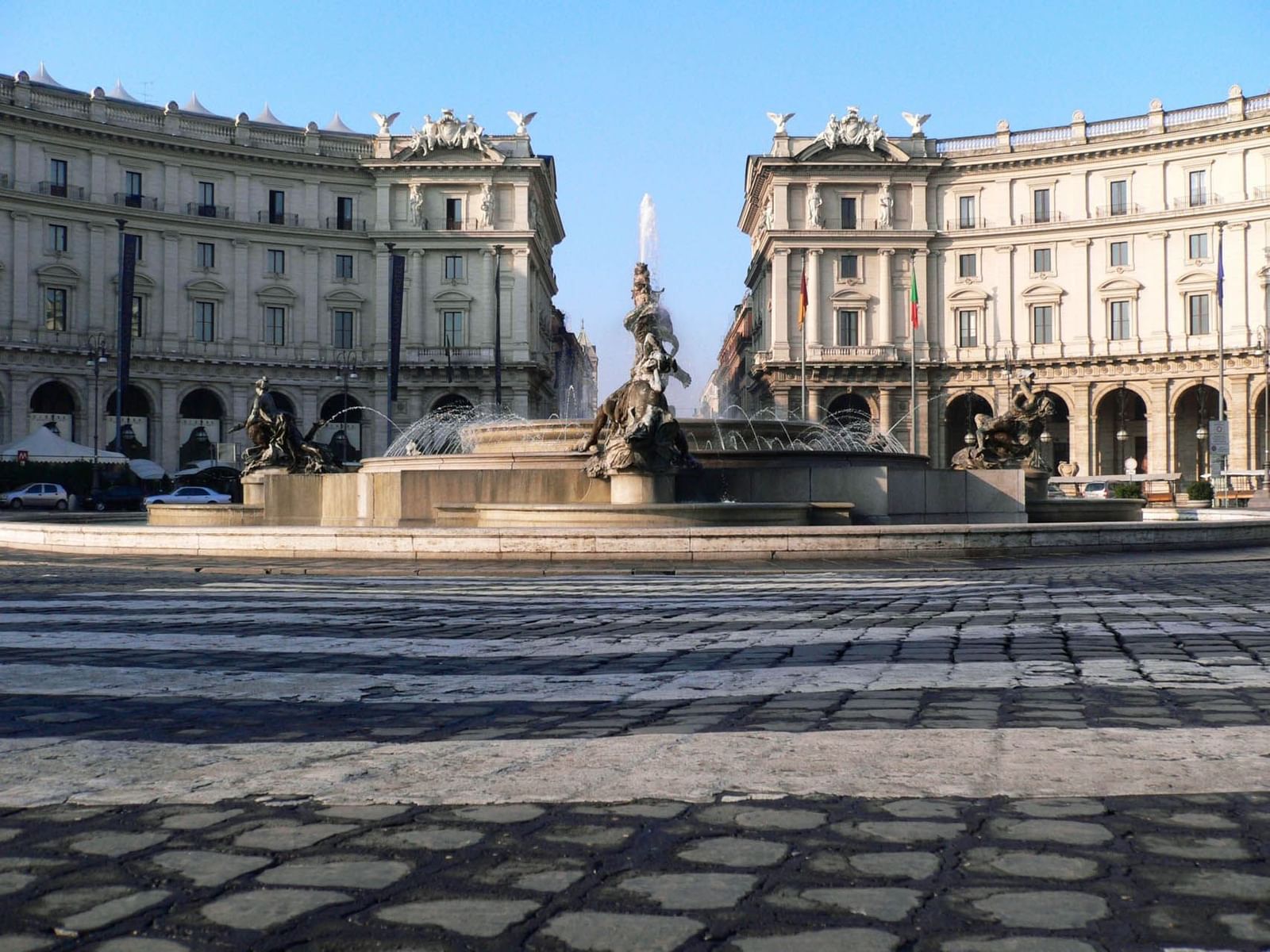 Sunny Piazza della Repubblica with water jets, cobblestone pavement, and historic buildings near The Guardian Hotel