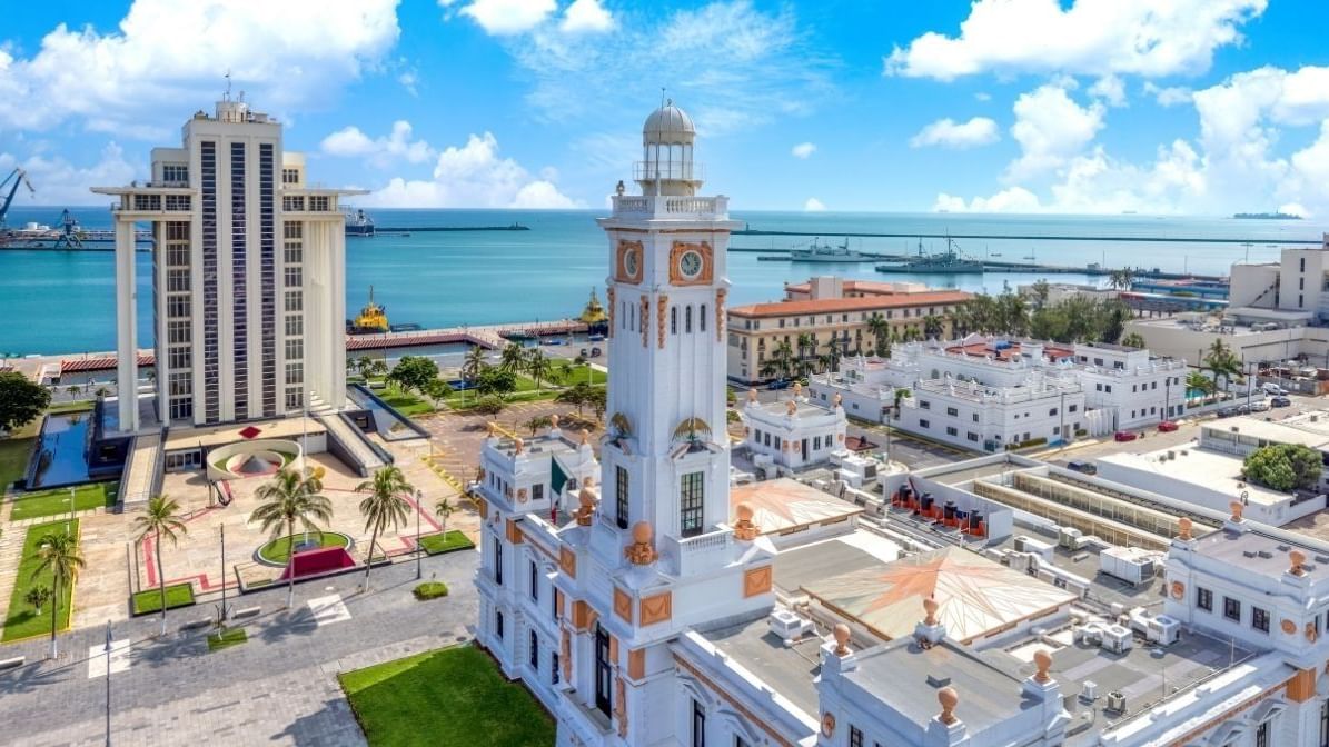 Torre histórica blanca junto al océano en México con puerto concurrido cerca de Camino Real Veracruz