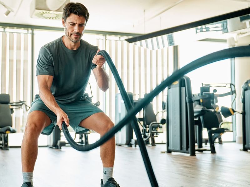 Uomo che si allena con una corda da battaglia in palestra.