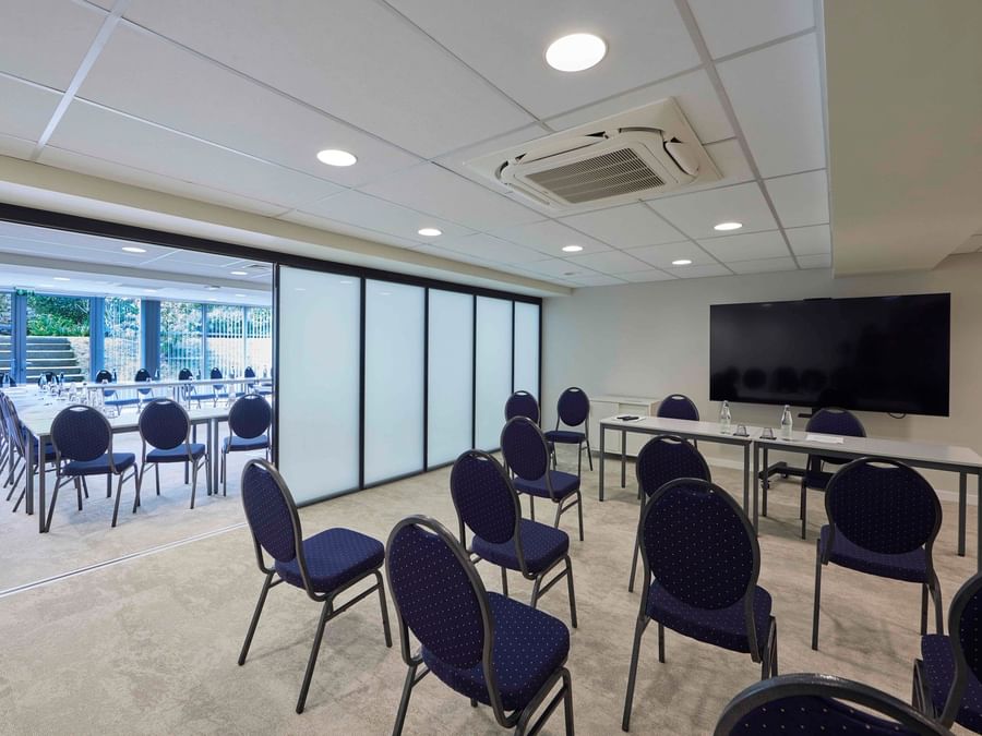 Salle de réunion moderne avec chaises bleues et grand écran à Hôtel La Marébaudière.