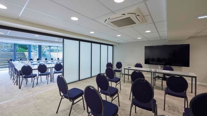 Salle de réunion moderne avec chaises bleues et grand écran à Hôtel La Marébaudière.