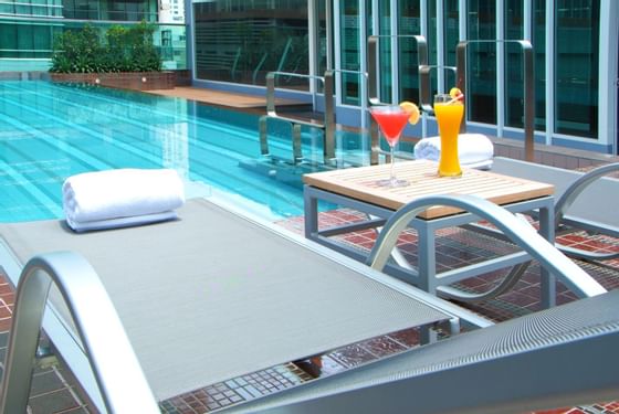 Two fruit juice glasses & bath towel by the pool at Amora Hotel