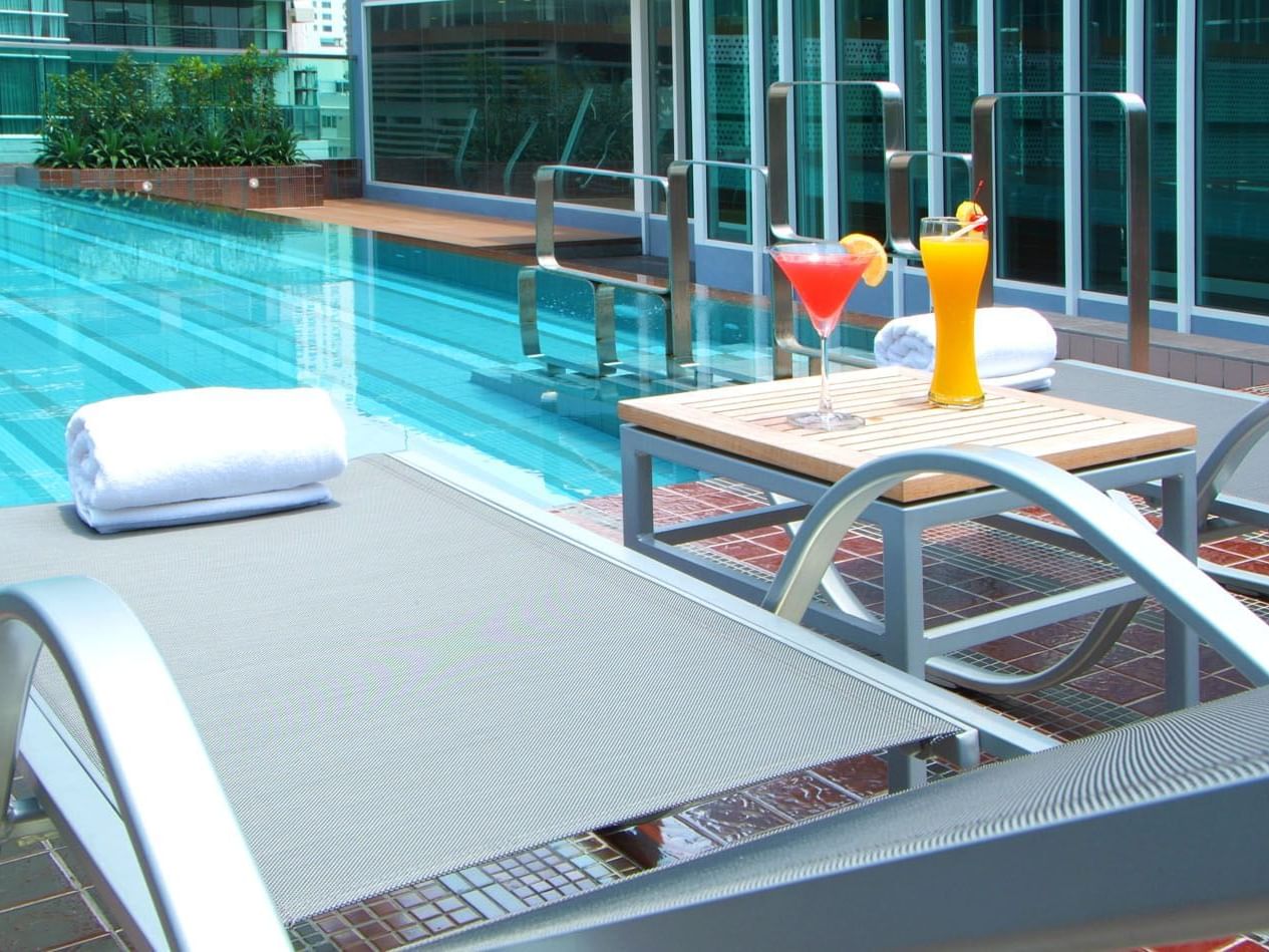Two juice glasses & Bath towels by the pool at Amora Hotel
