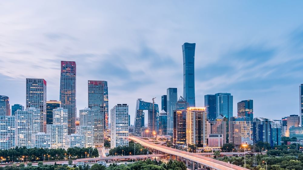City skyscrapers by a highway under a cloudy blue sky, surrounding a tall glass tower near warwick Hotels & Resort