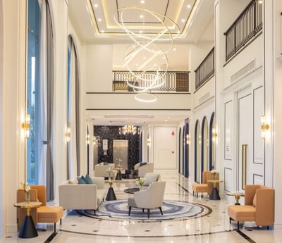 Lobby area with a chandelier, comfy sofas & wall lamps at Eastin Hotels