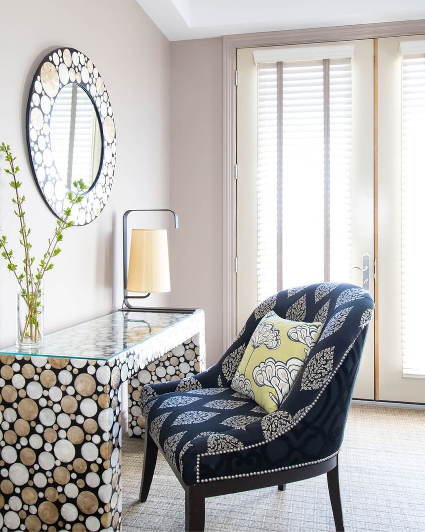 chair faces a decorative desk with matching mirror above near ba