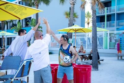 three people hi-five on a beach
