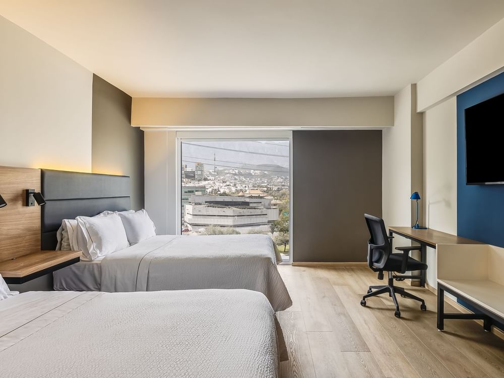 Two cozy beds with a work desk and wooden flooring in Executive Double room at Fiesta Inn