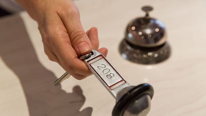A person hand holding a door key at Hotel L'Arc-En-Ciel