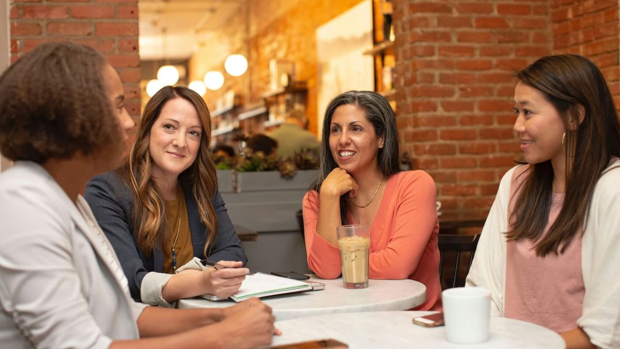 Four people on a corporate retreat in Canmore discuss ideas while drinking coffee.
