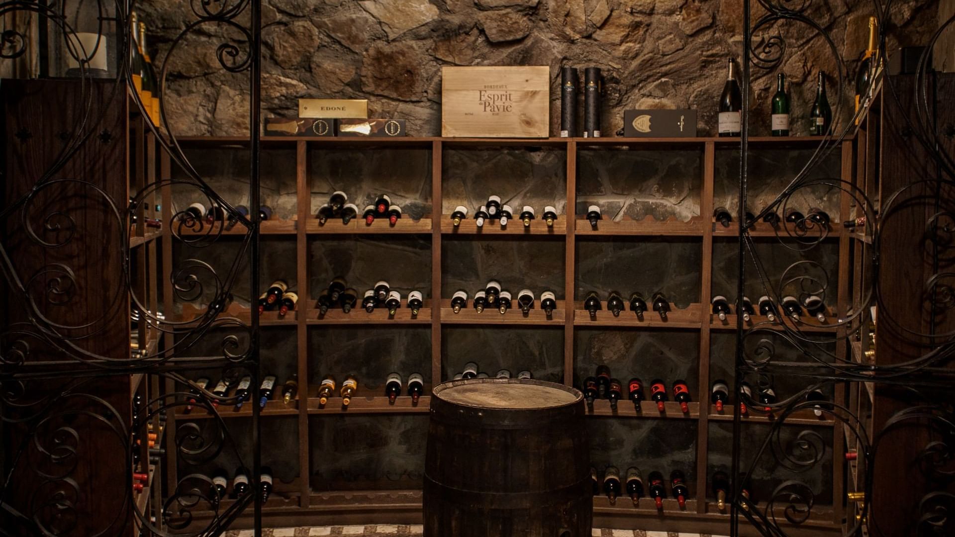 Acogedora bodega con paredes de piedra, una silla de cuero y botellas de vino en La Cava de Santiago en Hacienda del Mar Los Cabos