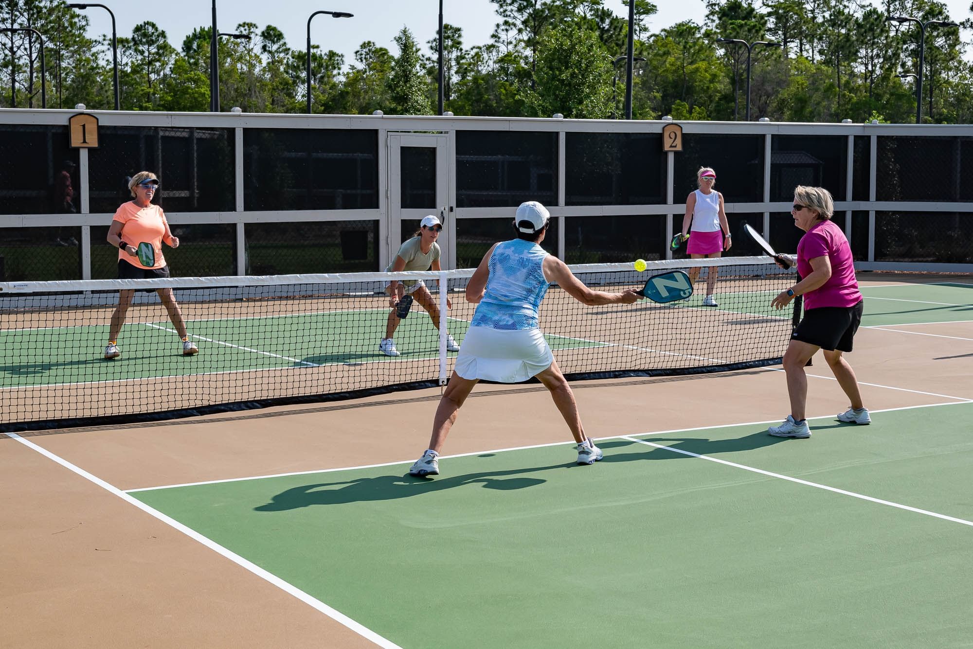 A group of Watersound Club Members volley on the pickleball court at the Camp Creek amenities.