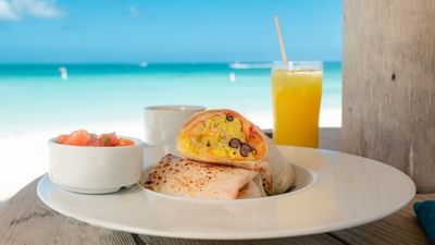 Egg Burrito served with fresh juice on beachside dining table at Passions on the Beach