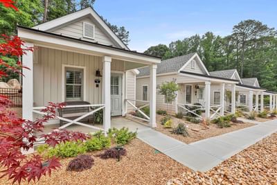 Lovely cottages with porches along gravel paths, surrounded by vibrant greenery in the Cottages at Laurel Brooke