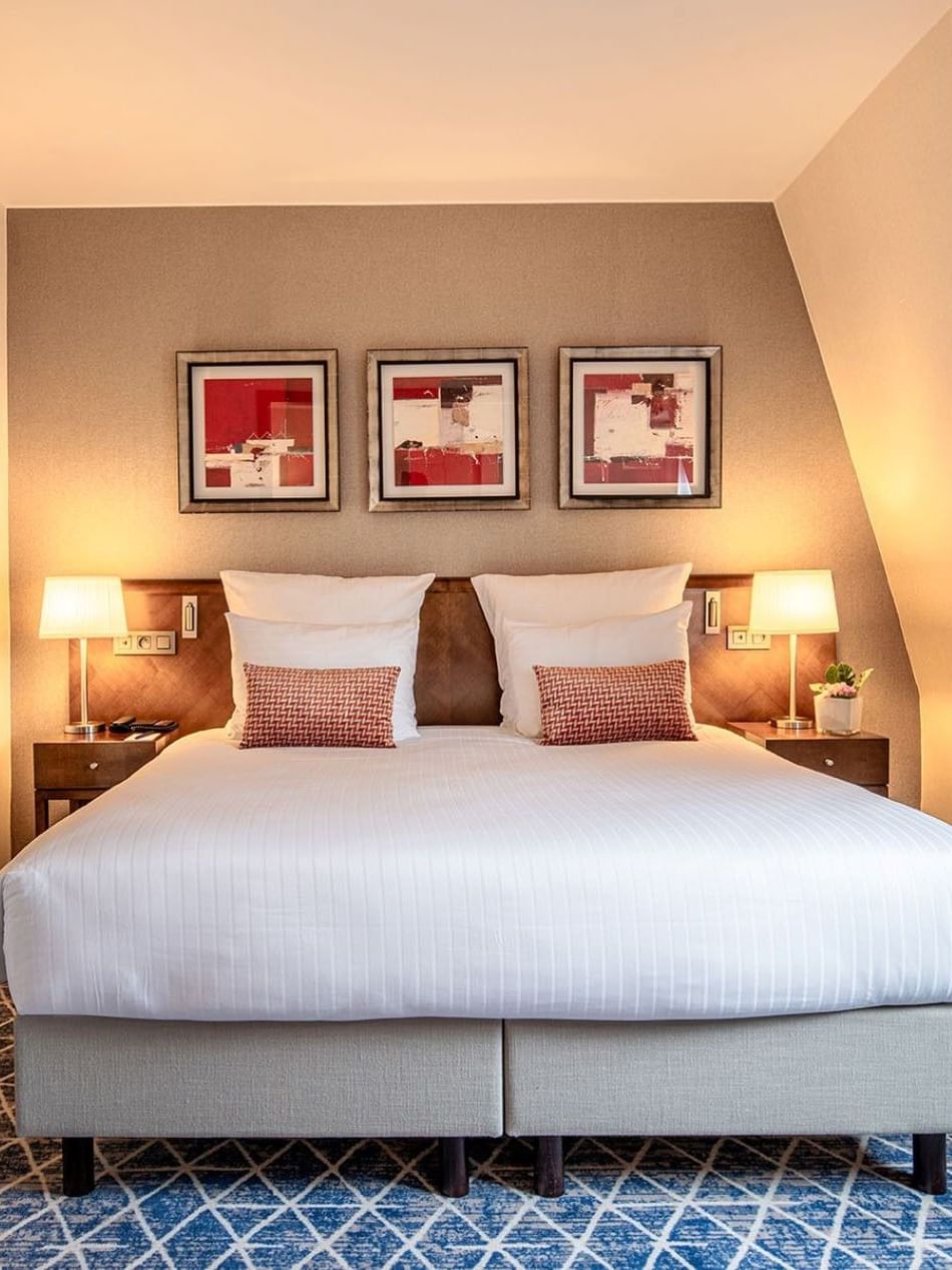 Bed with side tables near bathroom door in Junior Suite at Warwick Grand Place Brussels