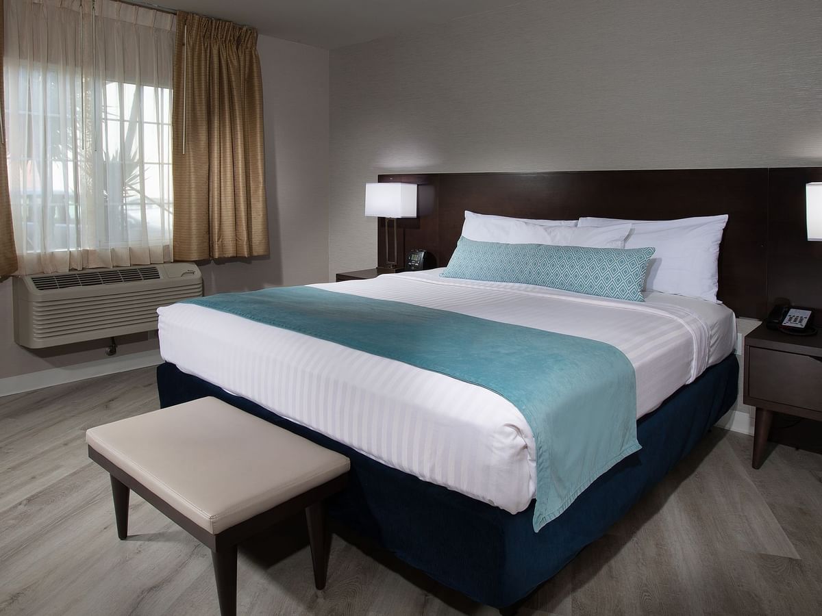 King bed with white and teal bedding, window, and nightstands