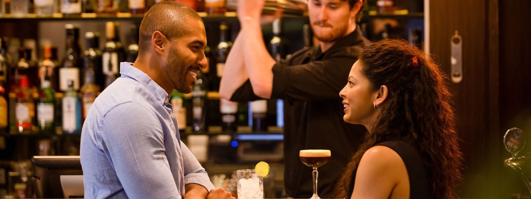 Couple at a bar with a bartender preparing drinks at Eat Street.