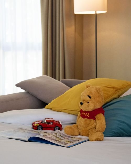 Teddy bear, toy car and open story book on the bed at Warwick Reine Astrid - Lyon