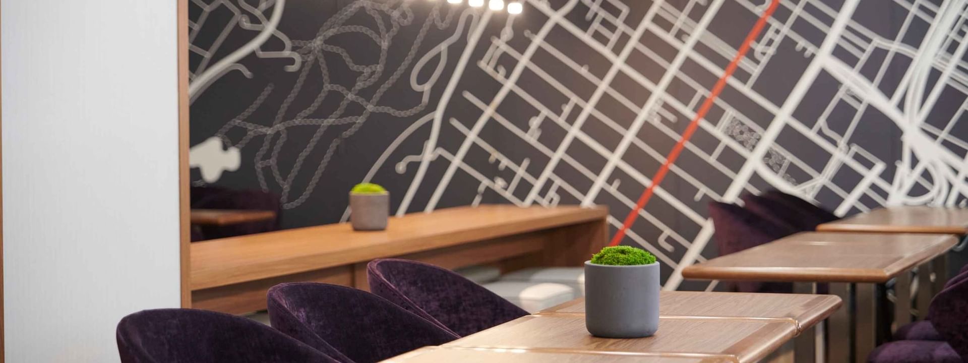 Espace Ste. Catherine à Warwick Le Crystal – Montréal avec des fauteuils violets moelleux et une carte de la ville affichée au mur.