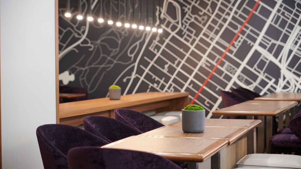 Espace Ste. Catherine à Warwick Le Crystal – Montréal avec des fauteuils violets moelleux et une carte de la ville affichée au mur.