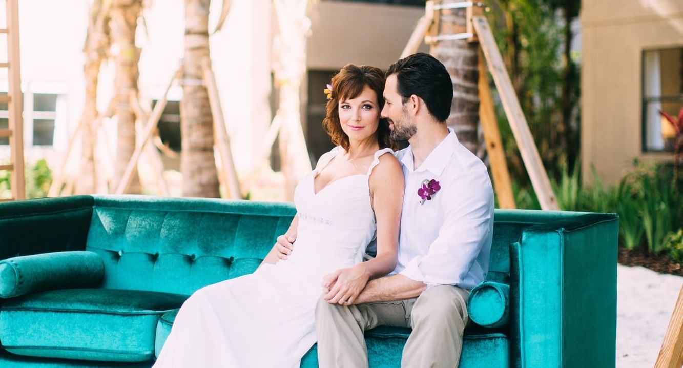 Wedded couple sitting on an outdoor couch and posing for a picture at The Grove Resort and Water Park