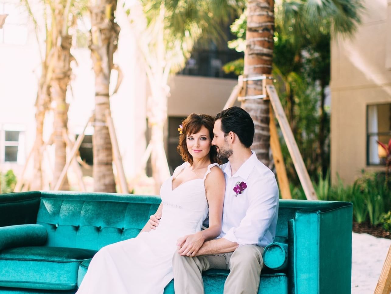 Wedded couple sitting on an outdoor couch and posing for a picture at The Grove Resort and Water Park