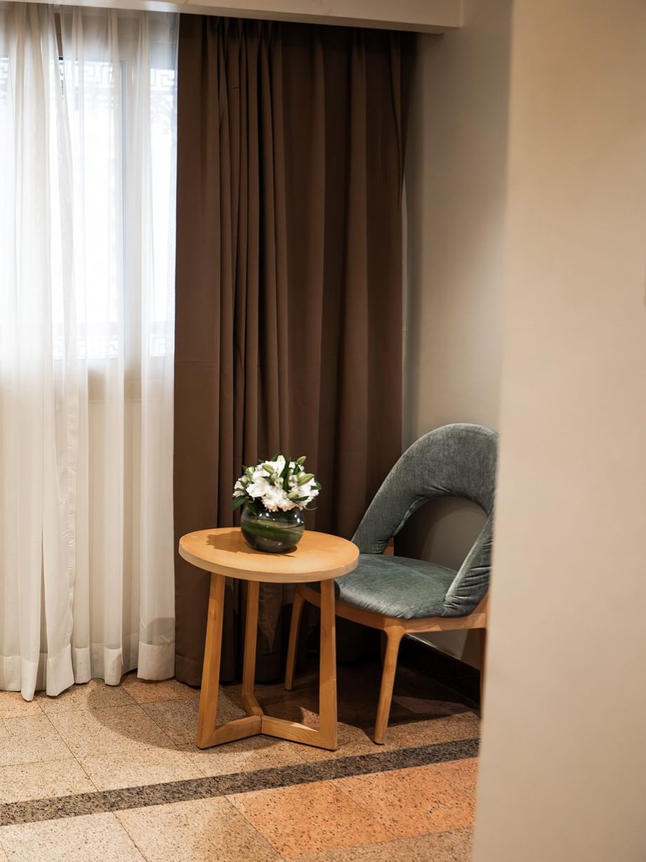 غرفة خماسية قياسية في فندق سجى ورويك المدينة المنورة، مزودة بكرسي وطاولة وستائر.