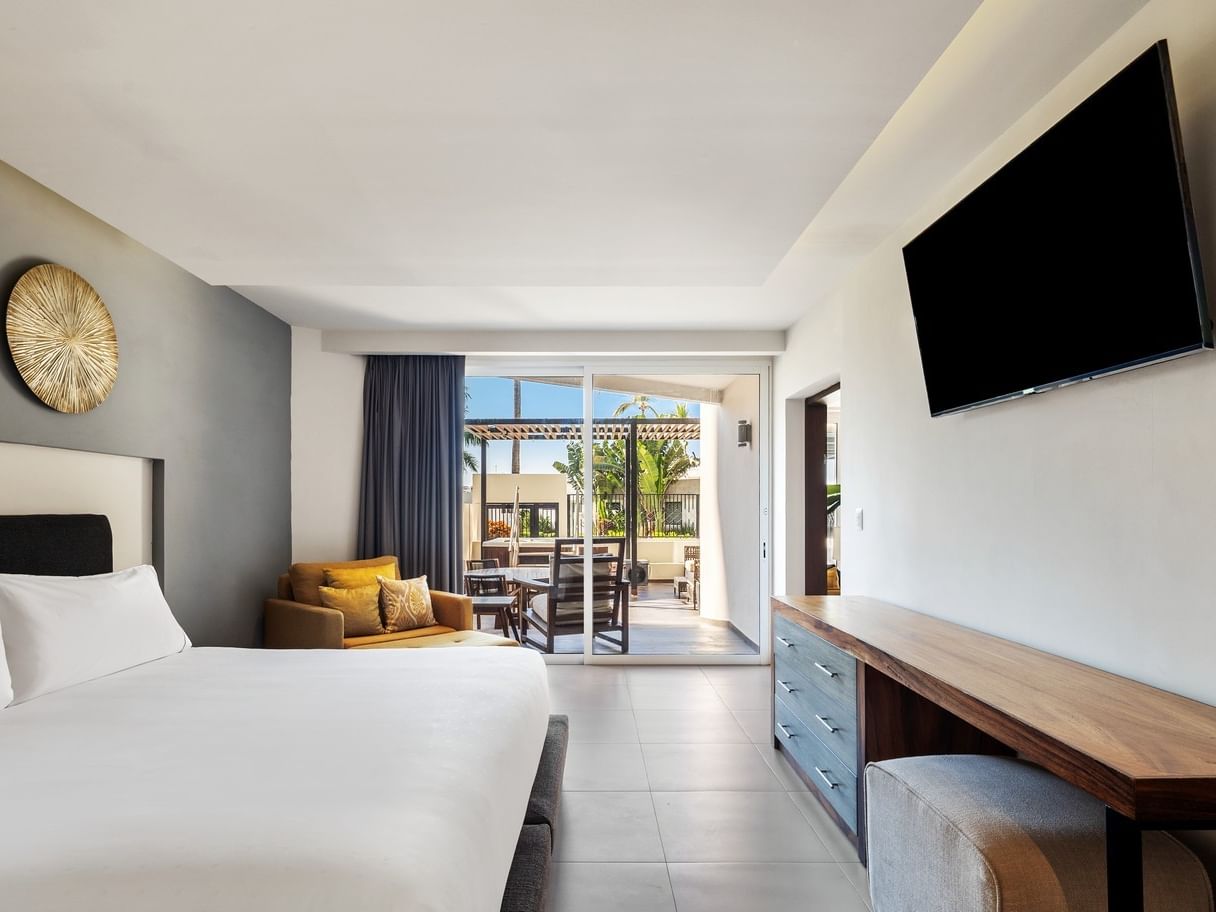 Villa Cora with a white cozy bed, a yellow armchair, and an entrance to a private patio at Sunvivia Mazatlán