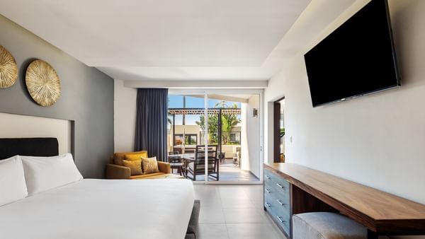 Villa Cora with a white cozy bed, a yellow armchair, and an entrance to a private patio at Sunvivia Mazatlán