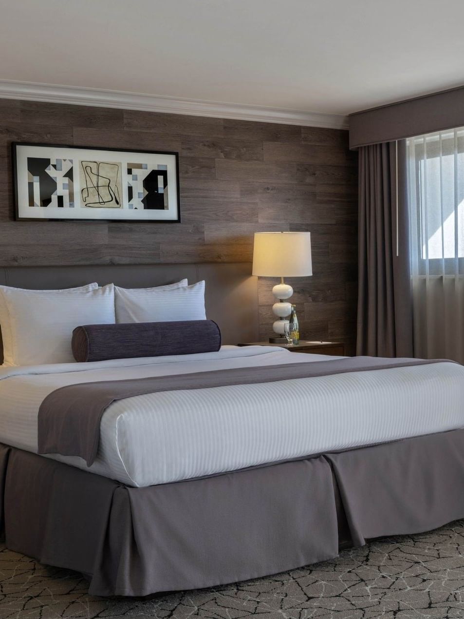 King bed by white lamps on dark nightstands under a decorative wood-slat wall in Premier Junior Suite at Warwick Denver