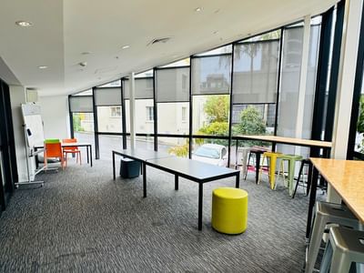 Open space with tables, chairs, and a yellow stool at UniLodge Auckland City.