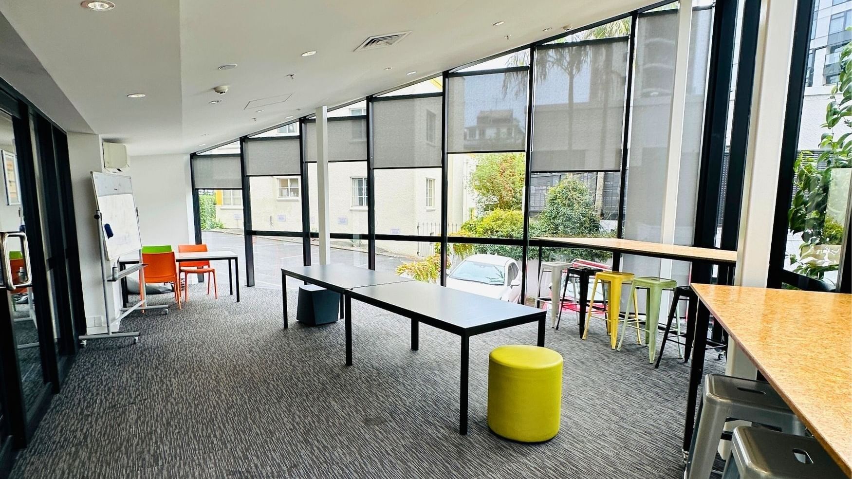 Open space with tables, chairs, and a yellow stool at UniLodge Auckland City.