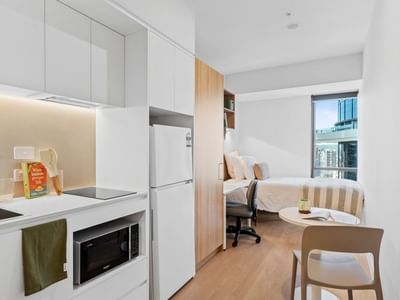 Modern hotel suite interior with white furniture and appliances at UniLodge Brisbane City.