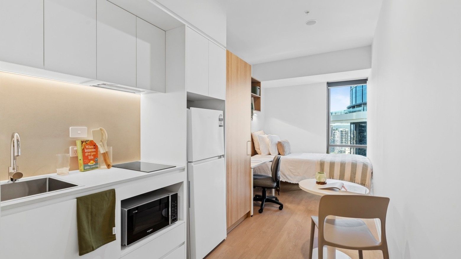 Modern hotel suite interior with white furniture and appliances at UniLodge Brisbane City.