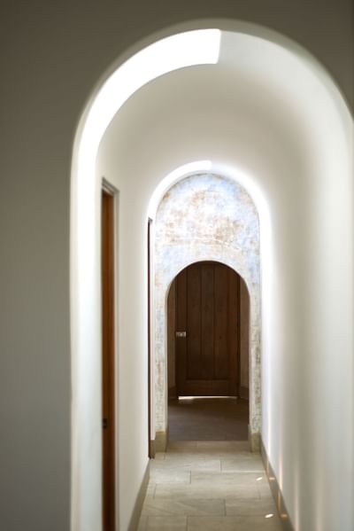 Sunlit, arched hallway with a vaulted ceiling leading to a wooden door at Singular Signature Residences
