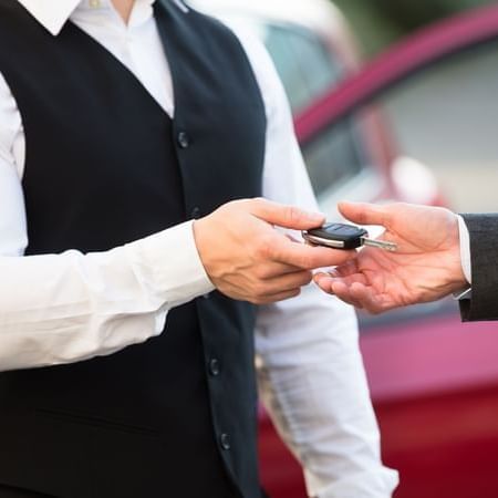 Close-up of a valet handing over a key at Warwick Le Crystal
