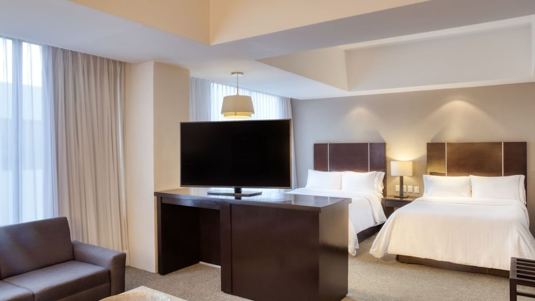 TV station & beds in Junior King Suite at Gamma Hotels
