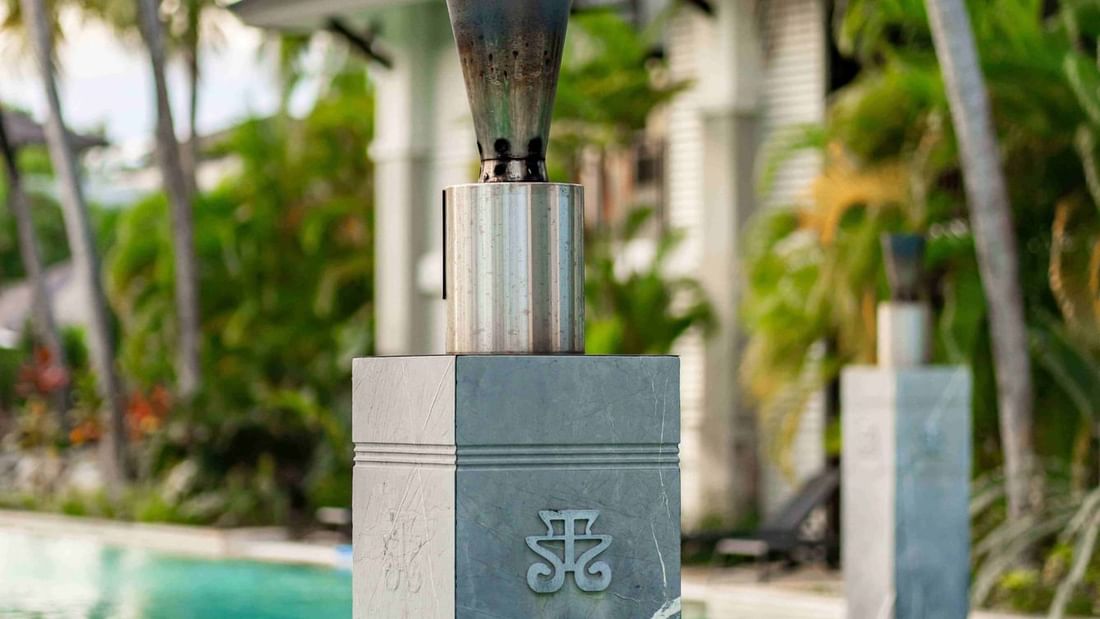 Close-up of lit torch atop a stone pillar by pool in Lagoon View Terrace at Pullman Port Douglas