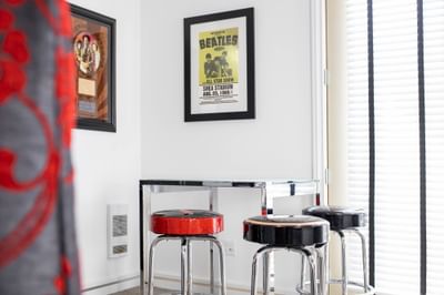 Dining table with stools in Queen Premiere Rock & Roll with posters of the Beatles on the wall at Retro Suites Hotel