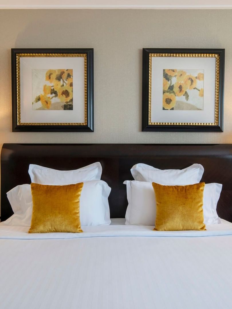 White pillows by yellow cushions under framed sunflower art in The Montaigne Suite at Warwick Paris Champs Elysées