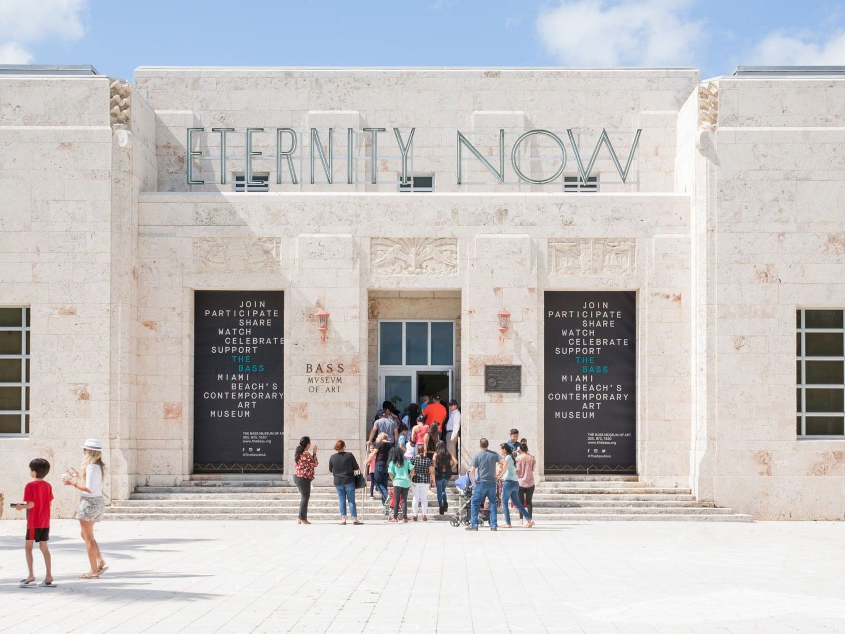 Crowd entering the imposing limestone Art Deco entrance of The Bass Museum of Art near Tradewinds Apartment Hotel